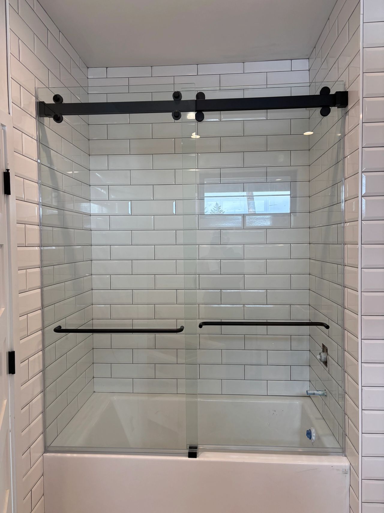A custom bypass glass shower door with white tile for a Whitefish MT client of Precision Glass
