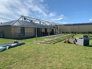Metal frame structure near a house under a clear sky.