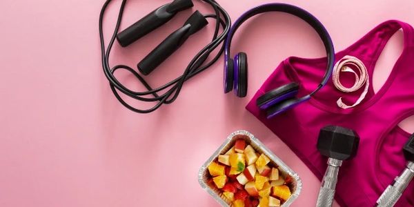 Fitness gear, healthy food, and accessories on a pink background.