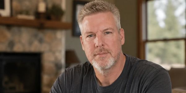 Middle-aged man with gray hair and beard in a cozy living room.