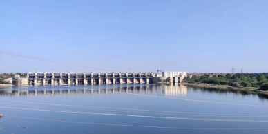 Wide view of a dam with calm water under a clear blue sky.