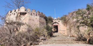 Ancient stone fort entrance with steps and trees under a clear blue sky.