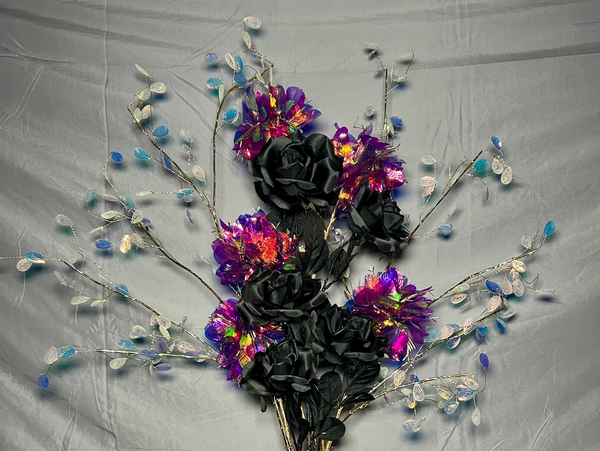 Bouquet of black roses and vibrant purple flowers with decorative branches.