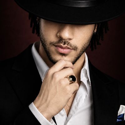 Stylish man in black hat and suit, with thoughtful pose.