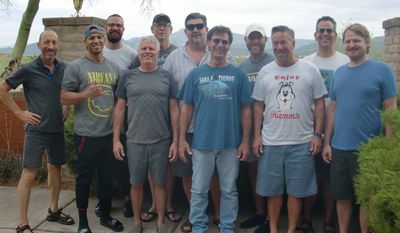 A group of ten men posing outdoors in casual clothes and sunglasses.