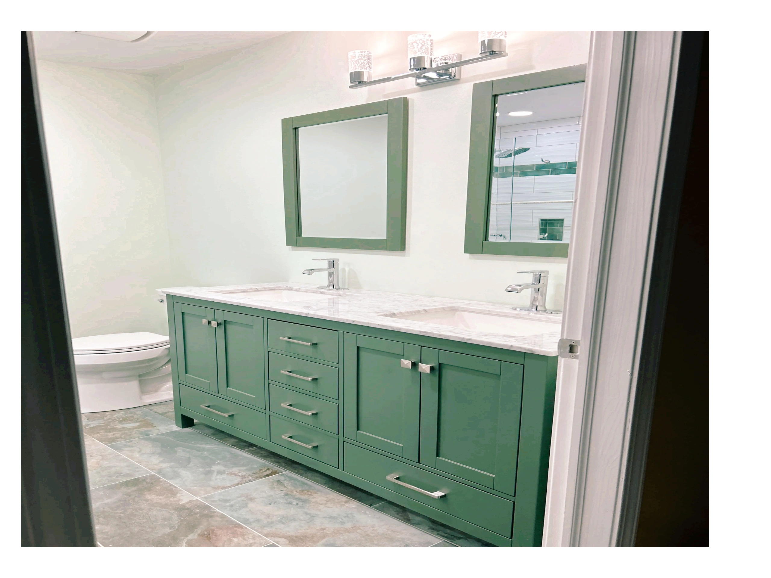 Modern bathroom with green cabinetry, double sinks, mirrors, lighting, and a tiled floor with hints of green. My client loved this idea.  