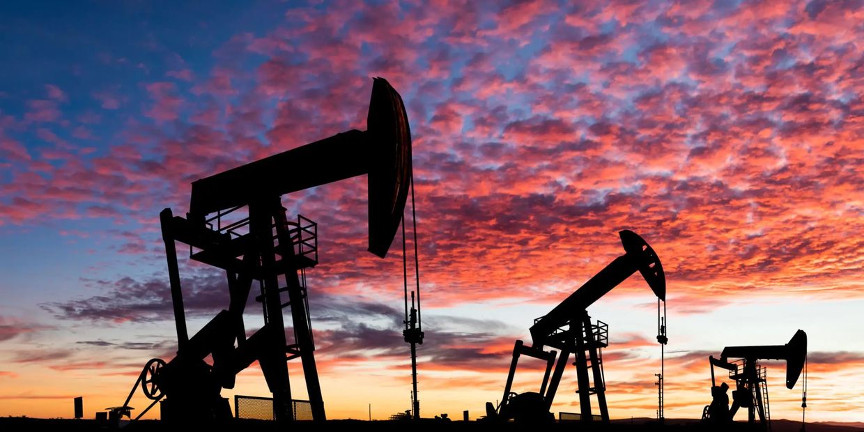 Silhouettes of oil pumpjacks against a colorful sunset sky.