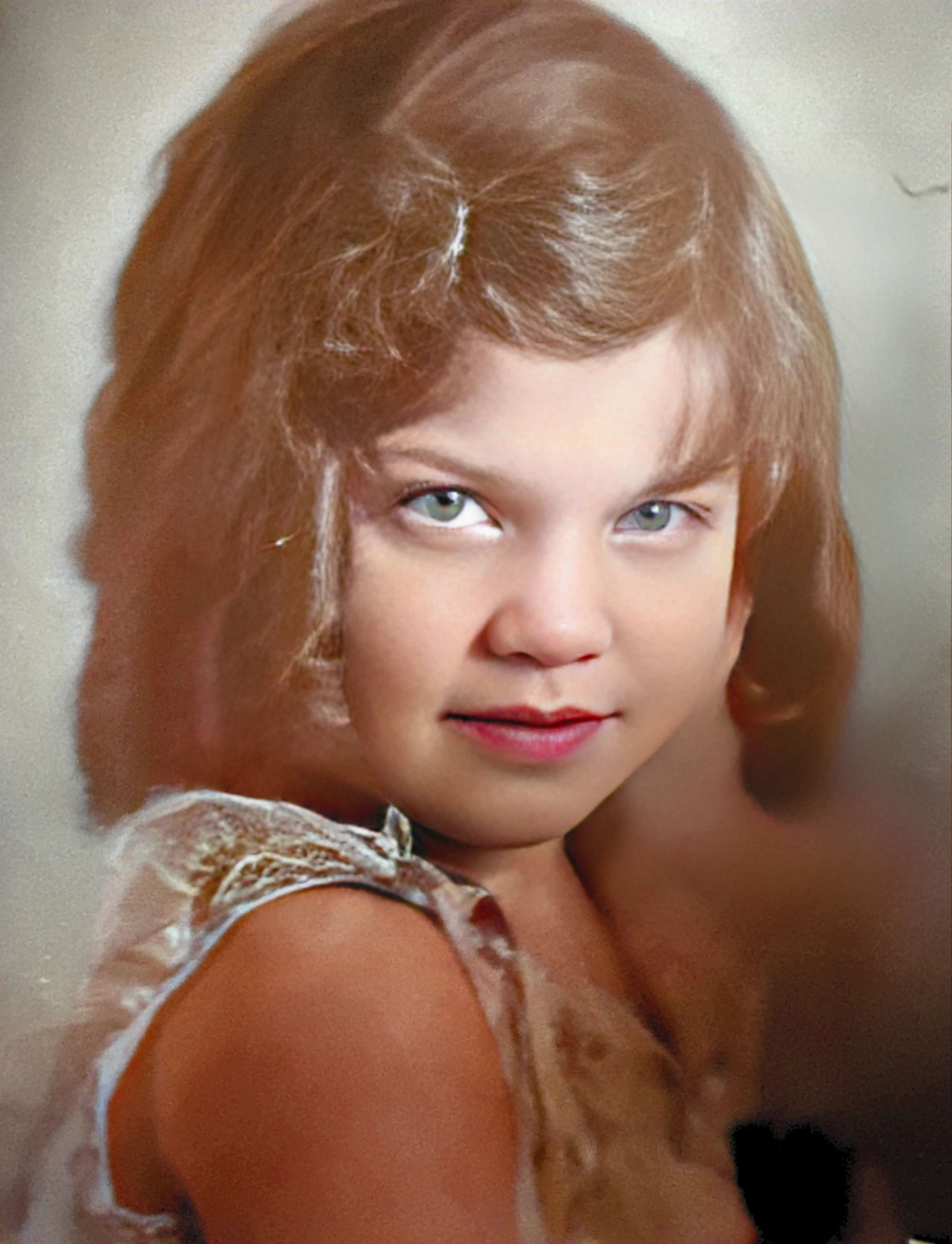 Young girl with light brown hair and green eyes, wearing a vintage dress.
