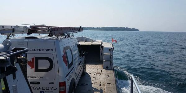 A work van on a ferry crossing the water to an island.