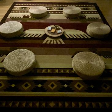 Round cushions arranged on a patterned rug around a small central tray.