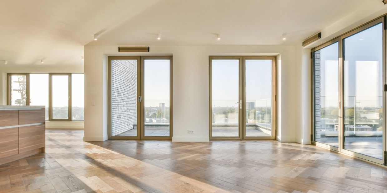Empty room with large glass doors and wood flooring.