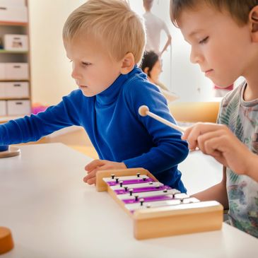 Two boys playing with musical instruments and toys in kindergarten