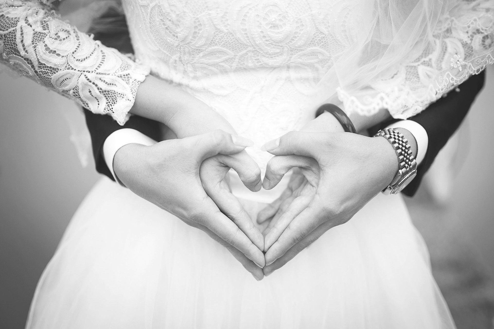 Close up of Bride and Groom's hands coupled together to form two love hearts