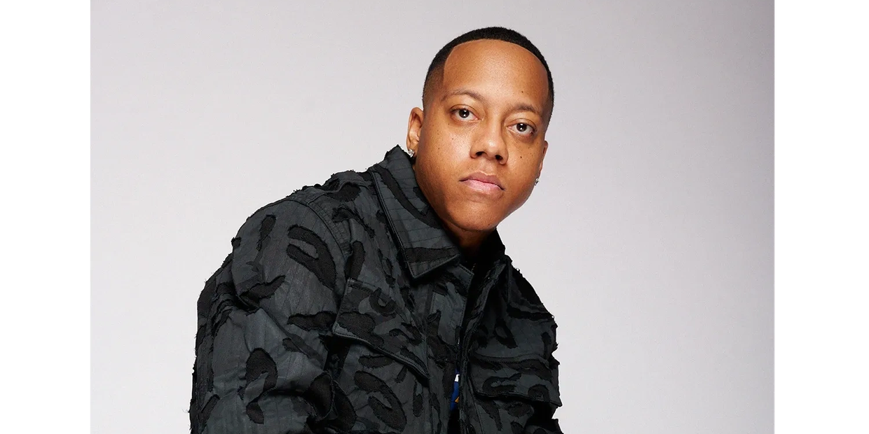 Man wearing a black patterned jacket and ripped jeans
