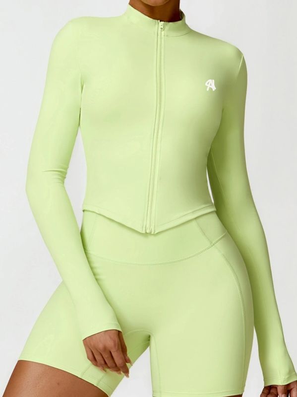 Woman wearing a light green fitted activewear set with long sleeves and bike shorts.