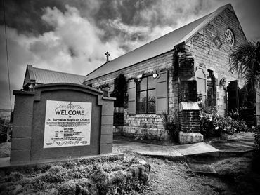 Black and white photo of St. Barnabas Anglican Church with welcoming sign.