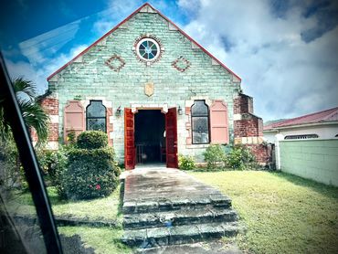 Old stone church with red doors and windows under a blue sky.