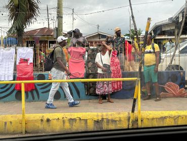 Street vendors selling clothes on a busy sidewalk with pedestrians.