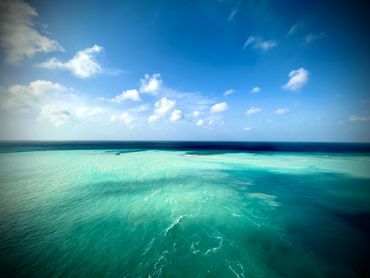 Clear turquoise ocean under a blue sky with scattered clouds.