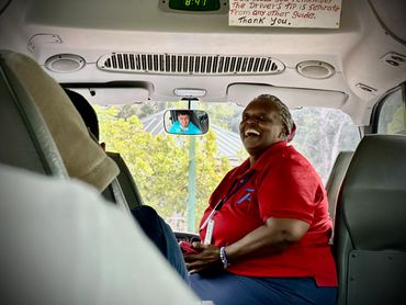 Smiling bus driver engaging with passengers inside the vehicle.