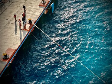 People fishing off a pier into the sea on a sunny day.