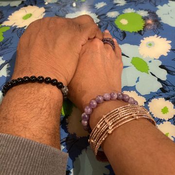 Two hands with bracelets clasped together.