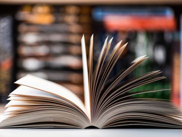 Open book with blurred bookshelf background.