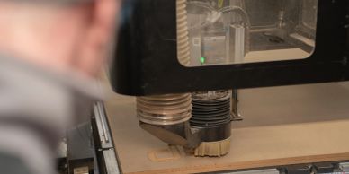 CNC machine cutting wood with a person observing.