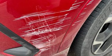 Red car fender scratched and dented.