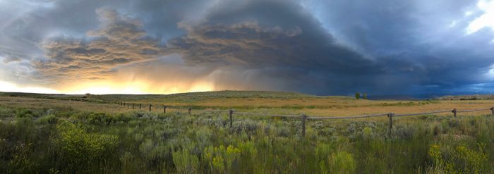 Panorama of a thunderstorm passing over sagebrush and fences, as the sun sets in Wyoming