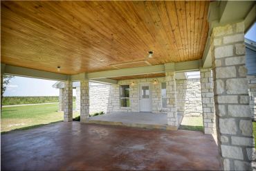 Covered outdoor patio with stone pillars and wooden ceiling.