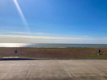 Sunny day overlooking a calm beach with clear blue sky.