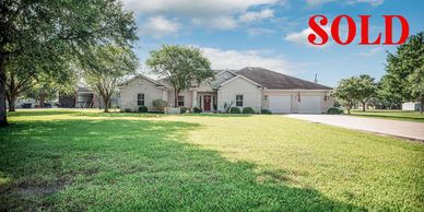 A single-story house with a large green lawn and "SOLD" in red letters.