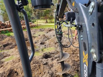 Close-up of an excavator drilling holes in the ground outdoors.