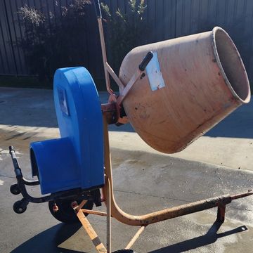 A portable cement mixer with a blue motor cover and orange drum.