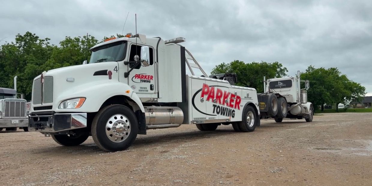 White Parker Towing truck towing another truck on a cloudy day.