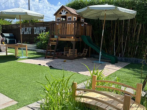 Outdoor children's play area with wooden playhouse and slide.