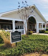 Entrance to Andrews Terrace with white pillars and green landscaping.