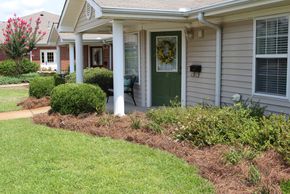 Well-maintained front porch with green door and lush landscaping.