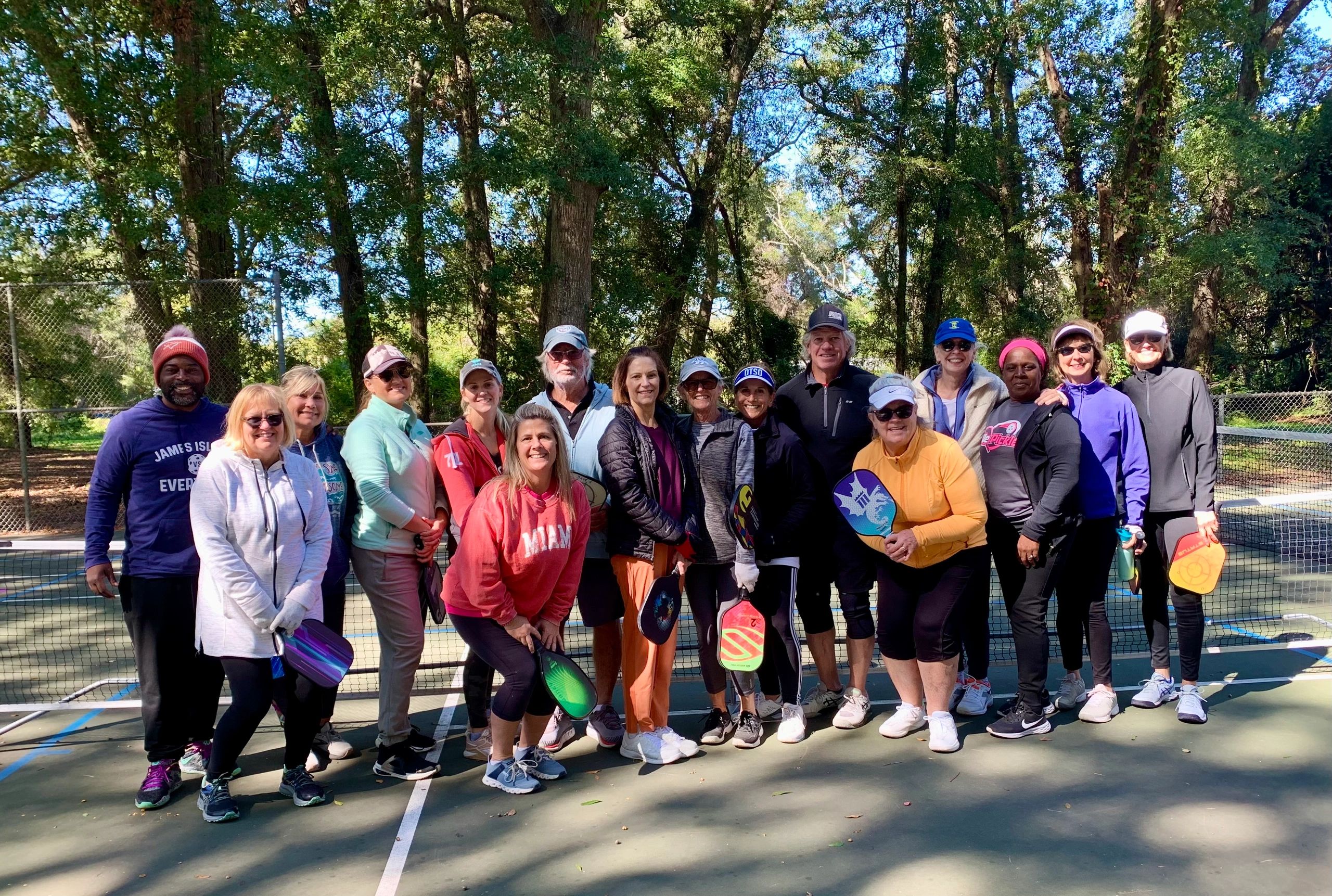 Group photo of pickleball players outdoors on a sunny day.