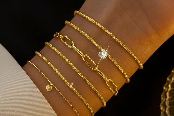 Close-up of a wrist adorned with five elegant gold bracelets, one with a sparkling diamond.