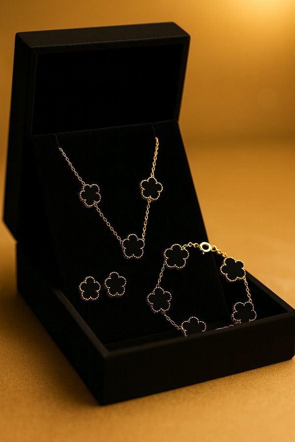Elegant gold jewelry set with flower motifs in a black velvet box.