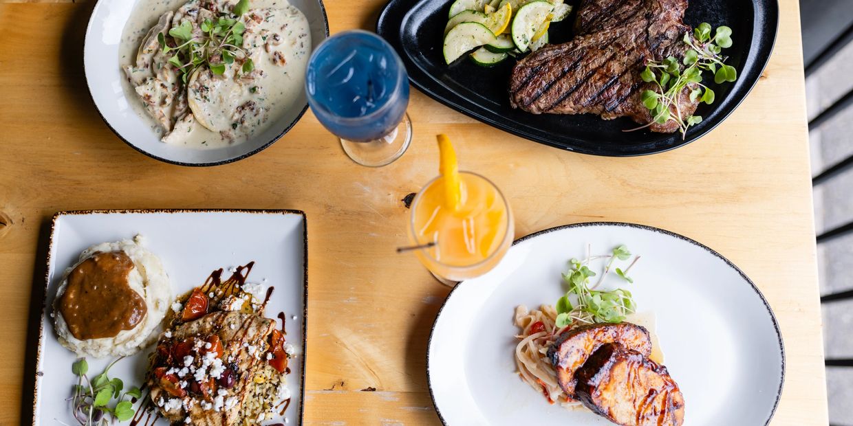 a table with four plates of food and two drinks 