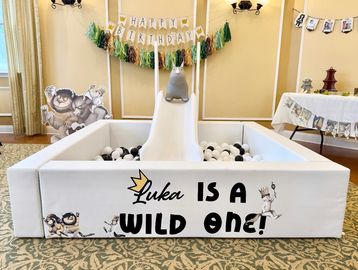 A playful birthday setup with a ball pit and animal decorations.