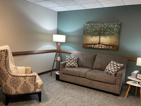 Cozy living room with patterned armchair, gray sofa, and warm lighting.