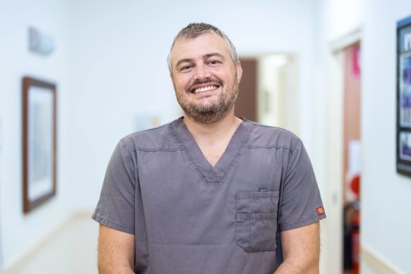 A photo of Dr Michael Vlismas smiling cheerily in a well lit dental practice.