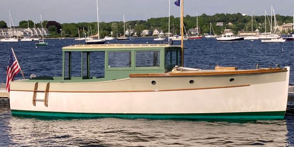 A classic motorboat with green and white colors docked near a marina.