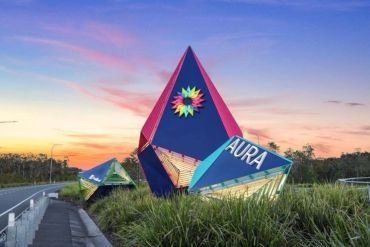 Large colorful AURA sign sculptures at a roadside.