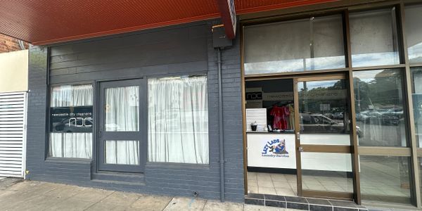 Exterior of a small shop with curtains and glass door.