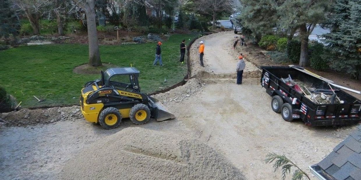 Construction machinery and workers preparing a dirt road.